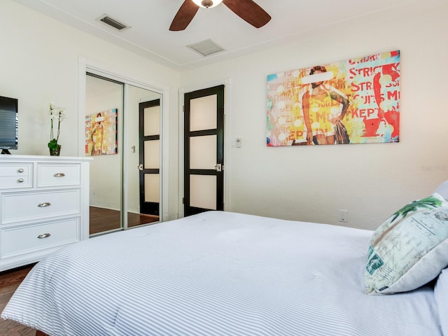 bedroom featuring a ceiling fan, visible vents, attic access, dark wood-style flooring, and a closet