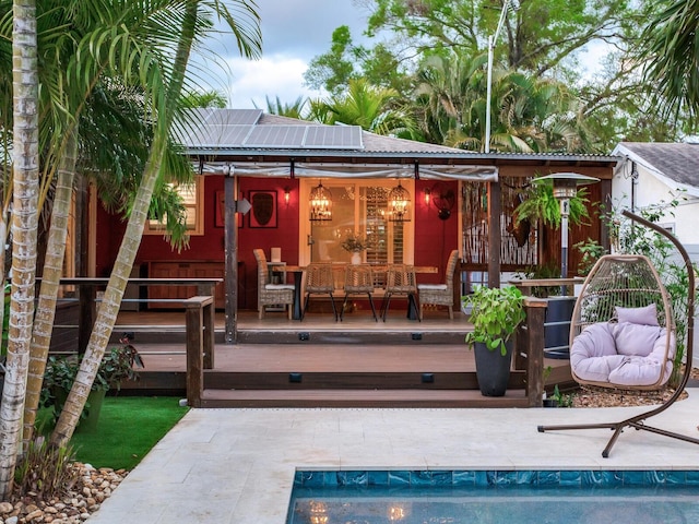 back of property with roof mounted solar panels and a wooden deck