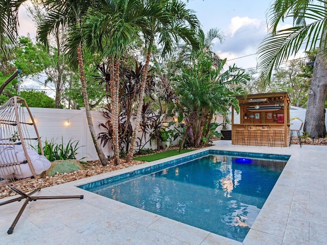 pool featuring outdoor dry bar, a patio area, and a fenced backyard