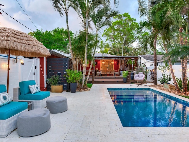 outdoor pool featuring a patio, a deck, and fence