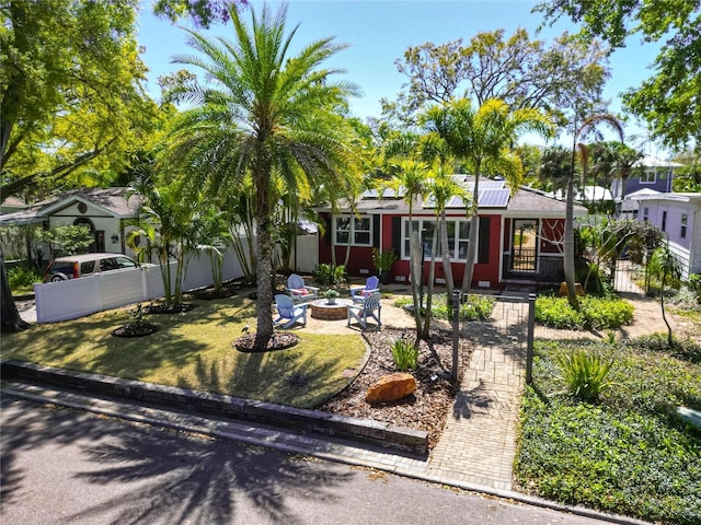 view of front of house featuring a patio area, roof mounted solar panels, an outdoor fire pit, and fence