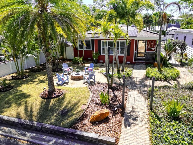 view of front of home featuring a patio, an outdoor fire pit, solar panels, a front lawn, and fence private yard