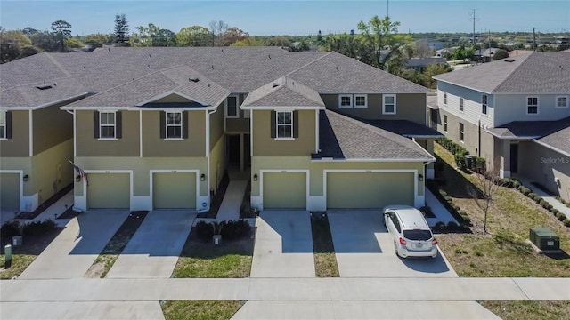 view of front of home with roof with shingles, driveway, stucco siding, a garage, and a residential view