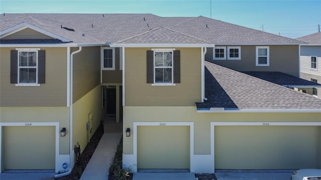 view of front of property featuring stucco siding, driveway, and a shingled roof