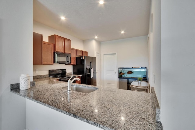 kitchen featuring a sink, stone countertops, brown cabinets, and black appliances