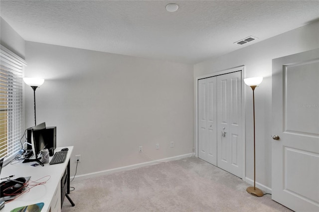 home office with a textured ceiling, light colored carpet, visible vents, and baseboards