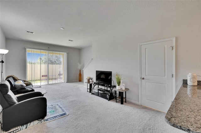 carpeted living area featuring baseboards, visible vents, and a textured ceiling