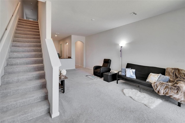 carpeted living room with arched walkways, visible vents, and stairs