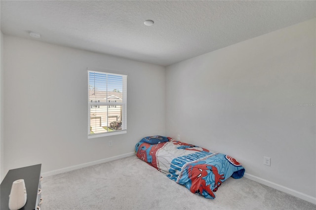 carpeted bedroom with baseboards and a textured ceiling