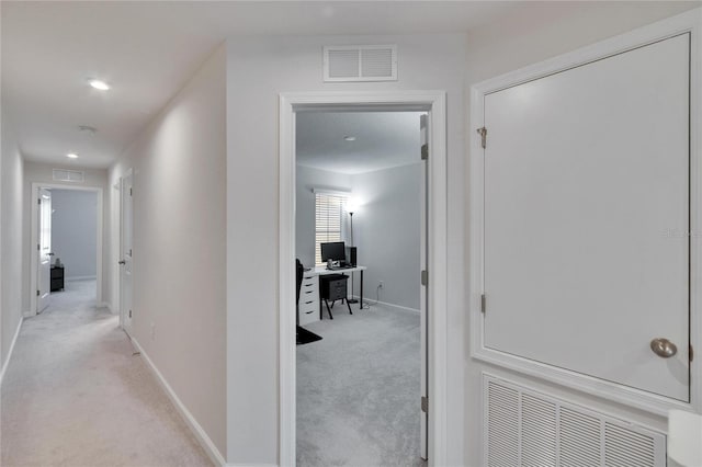 corridor with visible vents, light colored carpet, and baseboards