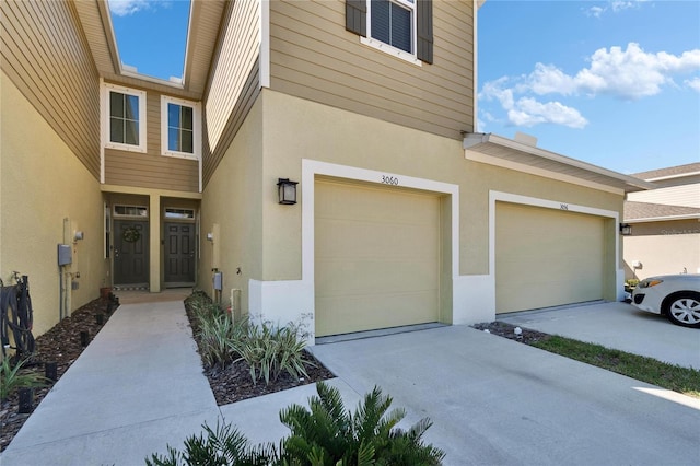 view of exterior entry featuring stucco siding, driveway, and an attached garage