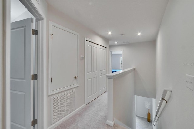 hallway featuring recessed lighting, visible vents, an upstairs landing, and light colored carpet