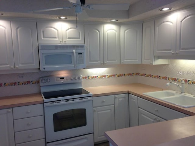 kitchen with white appliances, light countertops, tasteful backsplash, and a sink