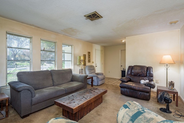 carpeted living area featuring visible vents, a textured ceiling, and baseboards