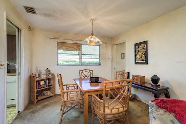 dining space featuring visible vents, a textured ceiling, carpet flooring, and a notable chandelier