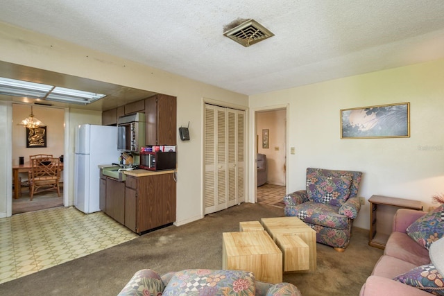 living area featuring an inviting chandelier, light carpet, visible vents, and a textured ceiling