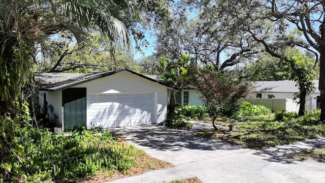 garage featuring concrete driveway and fence