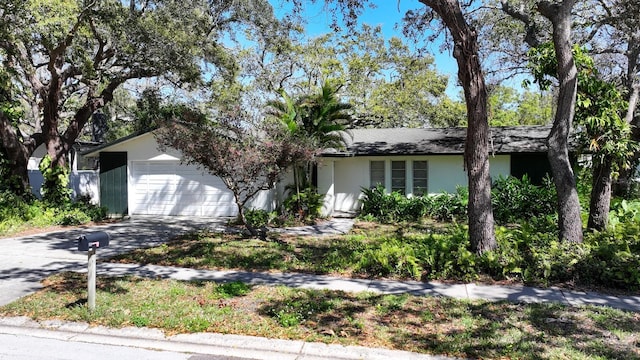 single story home with stucco siding, an attached garage, and driveway