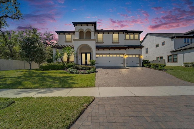 view of front of house with stucco siding, a front lawn, decorative driveway, fence, and a garage