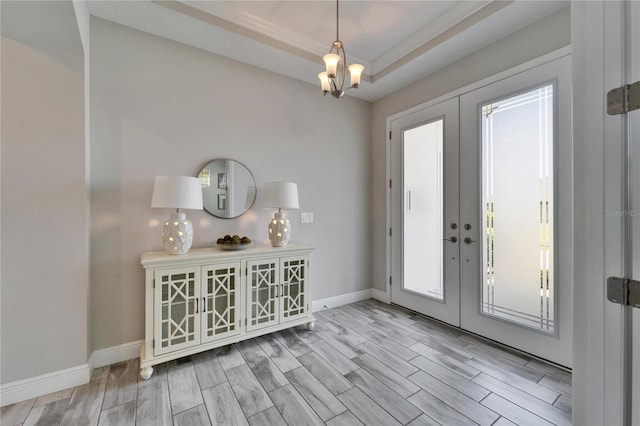 entrance foyer featuring a notable chandelier, french doors, baseboards, a raised ceiling, and wood tiled floor