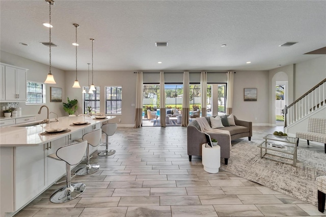 living area with arched walkways, visible vents, stairway, and baseboards