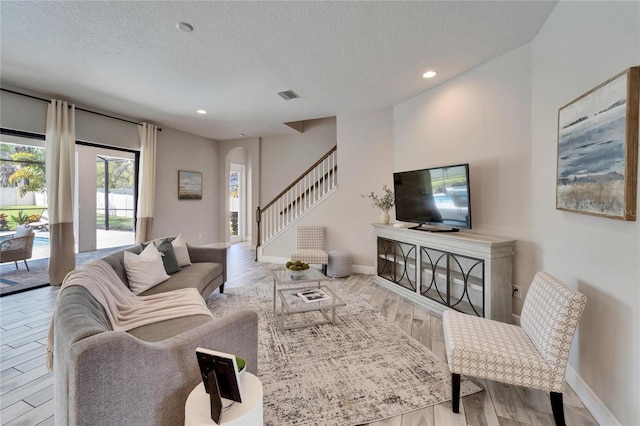 living area featuring stairs, visible vents, wood finished floors, and arched walkways