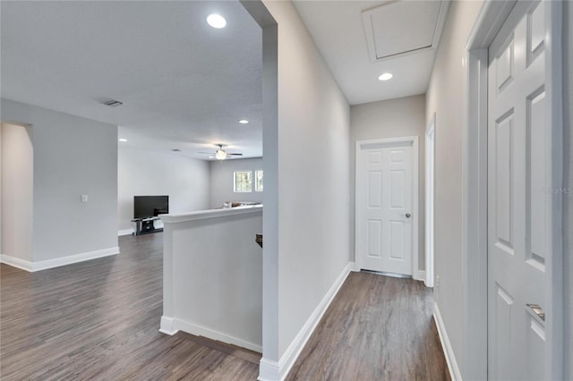 hallway with visible vents, dark wood-style floors, an upstairs landing, and baseboards