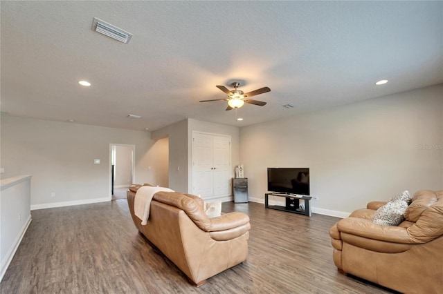 living area with a textured ceiling, wood finished floors, visible vents, and baseboards