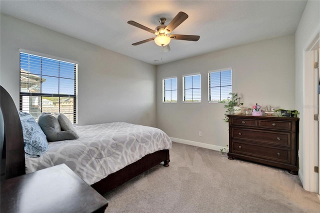 bedroom featuring multiple windows, light carpet, baseboards, and ceiling fan