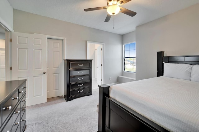 bedroom with connected bathroom, light colored carpet, and ceiling fan