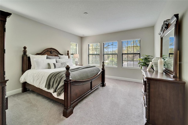 bedroom with light carpet, a textured ceiling, and baseboards