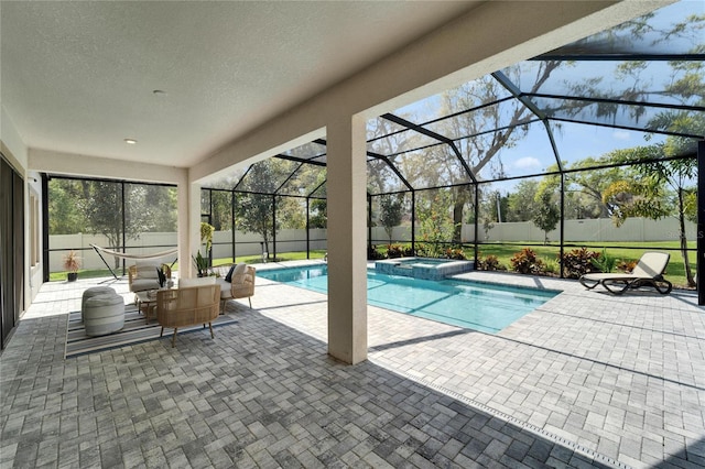 view of swimming pool featuring a patio, a fenced backyard, a pool with connected hot tub, and a lanai