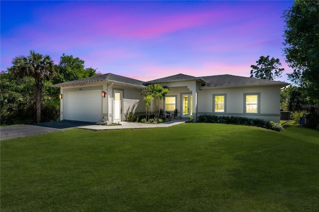 prairie-style home featuring aphalt driveway, a garage, a front yard, and stucco siding