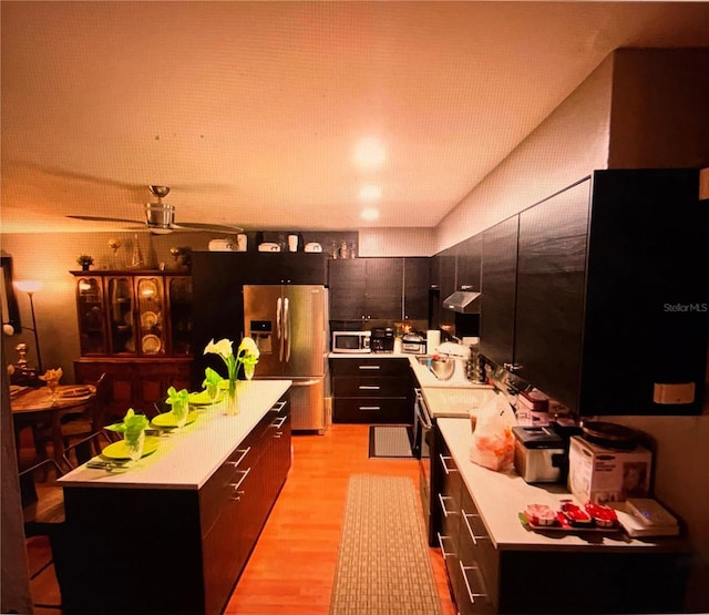 kitchen with under cabinet range hood, a center island, stainless steel appliances, light countertops, and ceiling fan