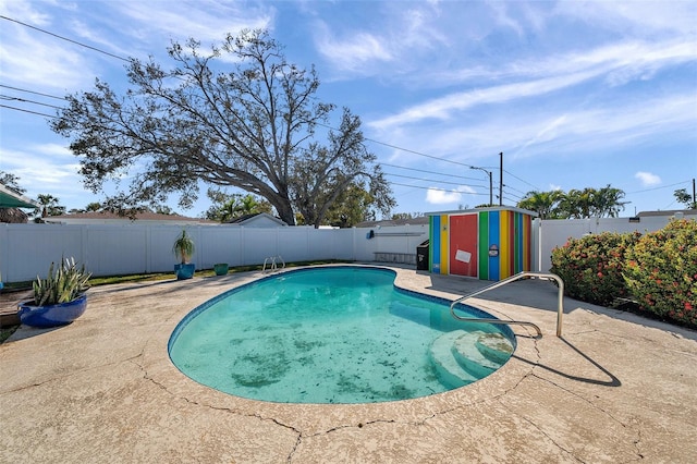 view of pool featuring a storage shed, a patio, an outdoor structure, and a fenced backyard