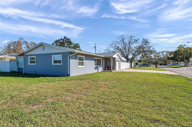 view of front of house featuring an attached garage, fence, driveway, stucco siding, and a front lawn