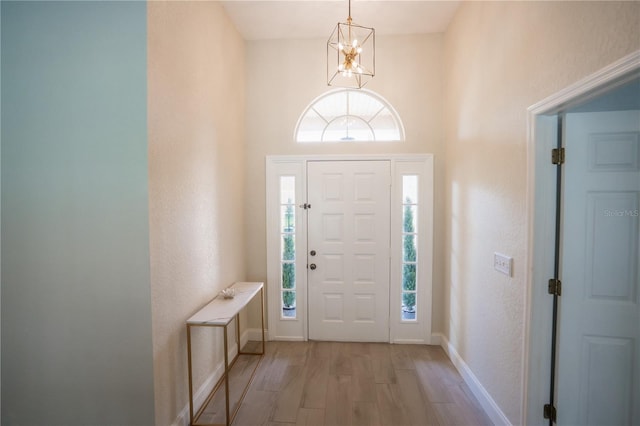 foyer entrance featuring an inviting chandelier, baseboards, and light wood-type flooring