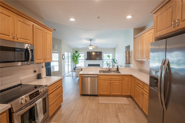 kitchen featuring open floor plan, light countertops, appliances with stainless steel finishes, a peninsula, and a sink