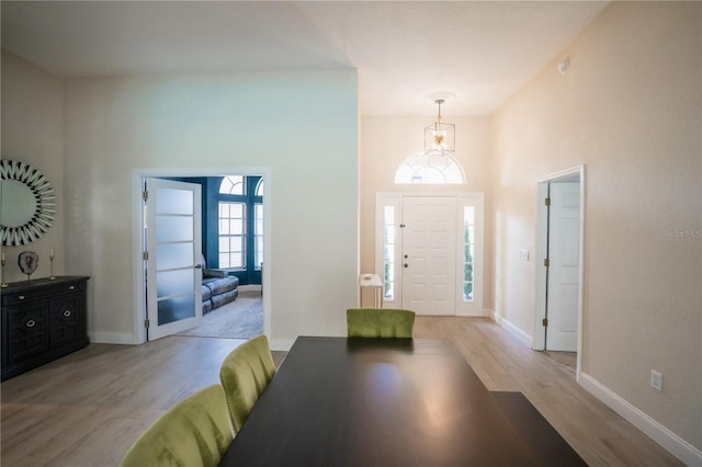 entrance foyer featuring baseboards, a towering ceiling, and light wood finished floors