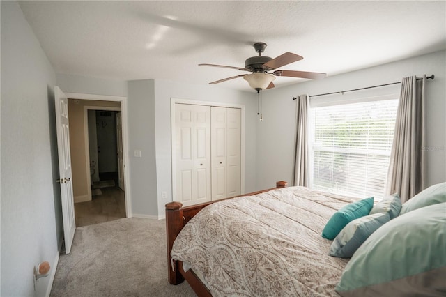 carpeted bedroom with a closet, baseboards, and ceiling fan