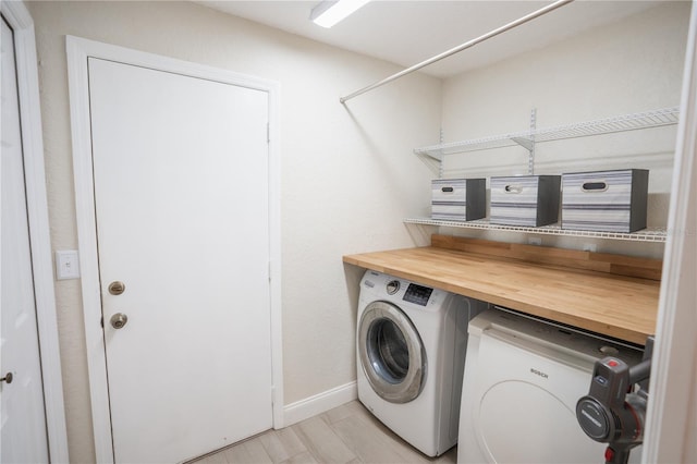 clothes washing area with baseboards, washing machine and dryer, and laundry area