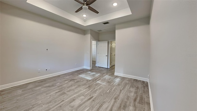 unfurnished bedroom with visible vents, baseboards, recessed lighting, light wood-style flooring, and a raised ceiling