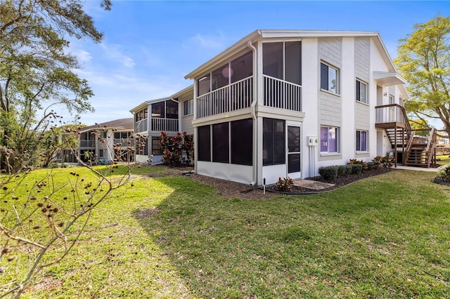 back of property featuring a sunroom, stairs, and a lawn