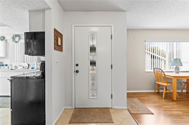 foyer entrance featuring a textured ceiling, baseboards, and light tile patterned floors