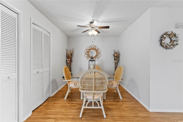 dining area with light wood-style flooring, baseboards, ceiling fan, and a textured ceiling