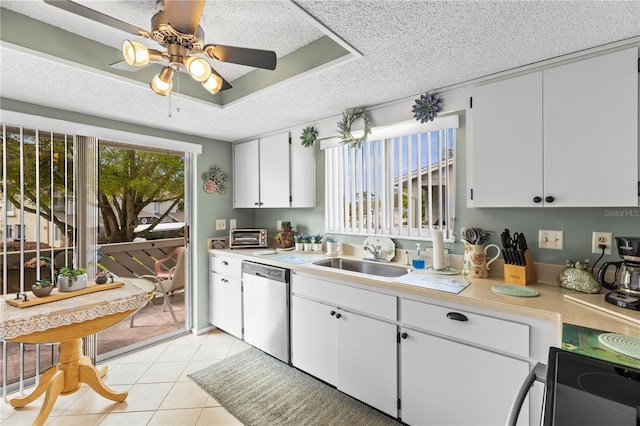 kitchen with light countertops, stainless steel dishwasher, light tile patterned flooring, a sink, and a textured ceiling