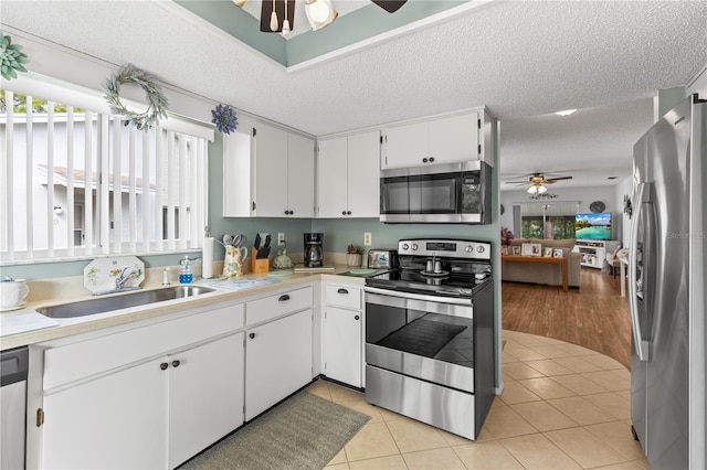 kitchen with light tile patterned floors, light countertops, appliances with stainless steel finishes, and a sink