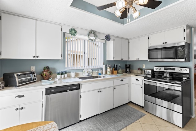 kitchen featuring light tile patterned floors, a textured ceiling, stainless steel appliances, light countertops, and a tray ceiling