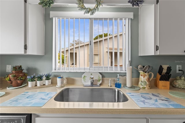 kitchen featuring light countertops, a sink, and white cabinetry