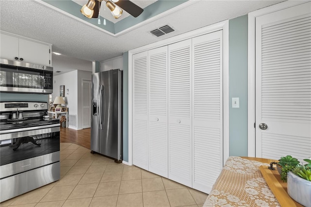 kitchen with light tile patterned floors, stainless steel appliances, visible vents, ceiling fan, and a textured ceiling